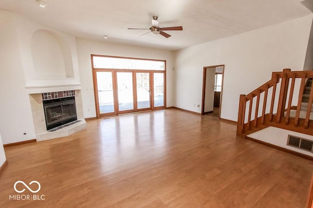 3948 S Woodfield Dr, New Palestine, IN 46163 - unfurnished living room with a ceiling fan, plenty of natural light, a tiled fireplace, and light wood finished floors