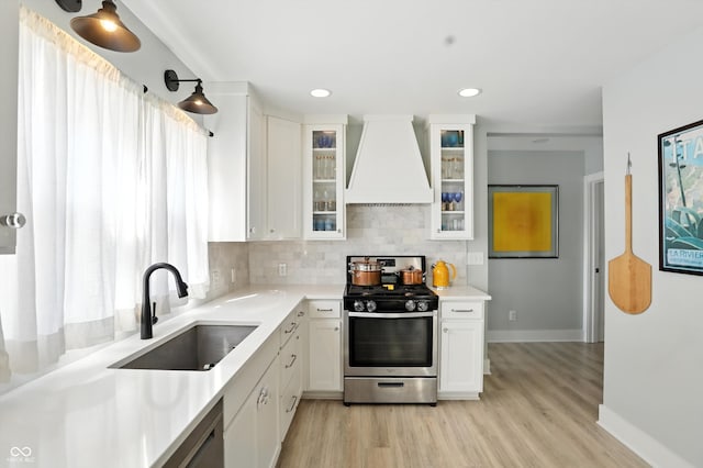 5312 Norwaldo Ave, Indianapolis, IN 46220 - kitchen featuring stainless steel range with gas stovetop, custom exhaust hood, white cabinetry, and light wood-style floors