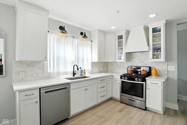 5312 Norwaldo Ave, Indianapolis, IN 46220 - kitchen featuring appliances with stainless steel finishes, custom range hood, white cabinets, light wood-style floors, and backsplash
