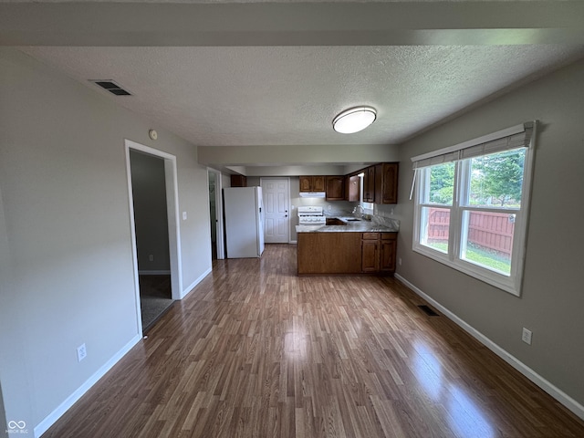 1206 Brownswood Dr, Brownsburg, IN 46112 - kitchen with white appliances, dark wood finished floors, open floor plan, a peninsula, and a textured ceiling