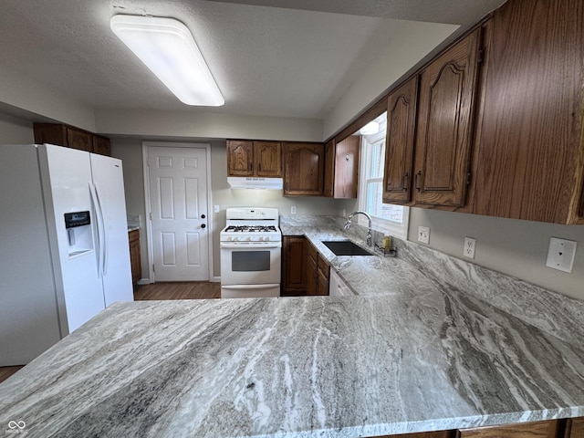 1206 Brownswood Dr, Brownsburg, IN 46112 - kitchen with white appliances, under cabinet range hood, wood finished floors, a peninsula, and a textured ceiling