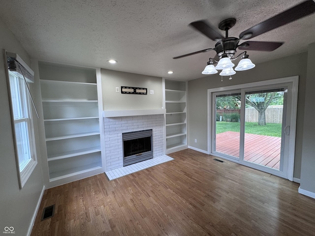 1206 Brownswood Dr, Brownsburg, IN 46112 - unfurnished living room featuring a textured ceiling, built in shelves, wood finished floors, ceiling fan, and a fireplace
