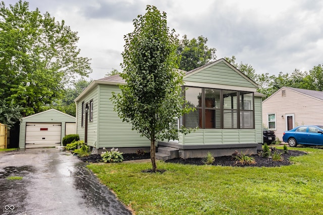 1710 N Irvington Ave, Indianapolis, IN 46218 - view of front facade featuring an outdoor structure, a detached garage, asphalt driveway, a front yard, and a sunroom