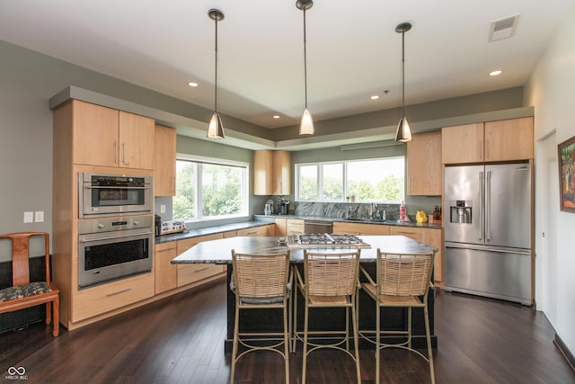 1036 Jackson St, Columbus, IN 47201 - kitchen featuring appliances with stainless steel finishes, dark wood-style flooring, a breakfast bar, decorative light fixtures, and recessed lighting