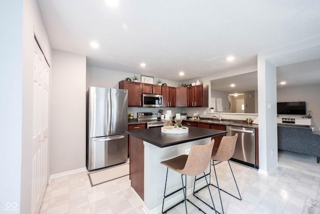 14459 Forsythia Ln, Fishers, IN 46038 - kitchen featuring appliances with stainless steel finishes, a breakfast bar area, light floors, dark countertops, and a center island