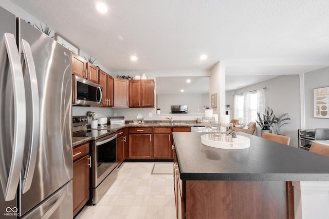 14459 Forsythia Ln, Fishers, IN 46038 - kitchen with stainless steel appliances, a center island, recessed lighting, dark countertops, and brown cabinetry