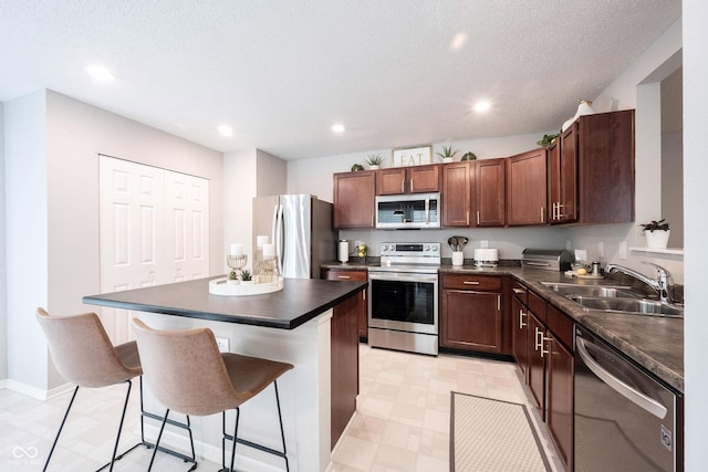 14459 Forsythia Ln, Fishers, IN 46038 - kitchen featuring appliances with stainless steel finishes, dark countertops, a breakfast bar area, a center island, and recessed lighting