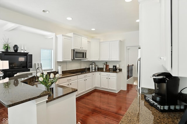 6570 Freemont Ln, Carmel, IN 46033 - kitchen with stainless steel microwave, white cabinets, dark wood-style flooring, dark stone counters, and recessed lighting
