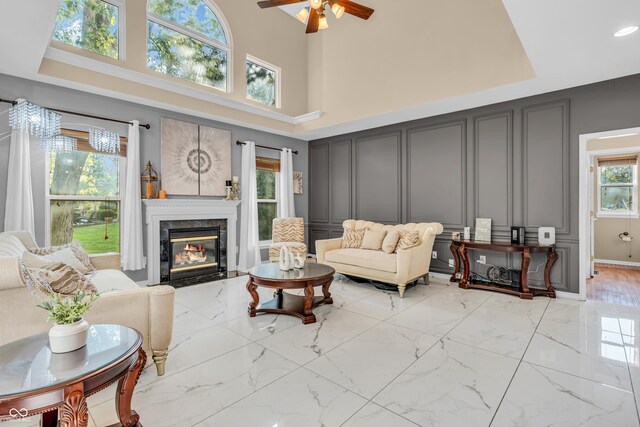 6374 Timberbluff Cir, Avon, IN 46123 - living area with a decorative wall, ceiling fan, a fireplace, a towering ceiling, and light marble finish floors