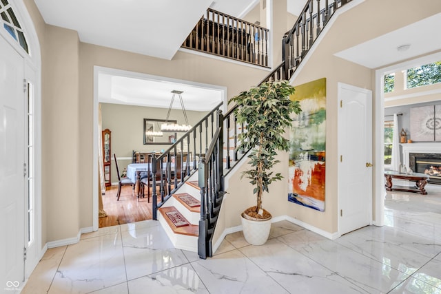 6374 Timberbluff Cir, Avon, IN 46123 - entrance foyer with marble tiled floors, stairs, a chandelier, and a glass covered fireplace