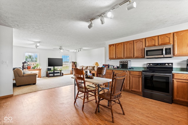 8638 W Flatwoods Rd, Gosport, IN 47433 - kitchen with black range with electric cooktop, stainless steel microwave, rail lighting, light wood-style floors, and a textured ceiling