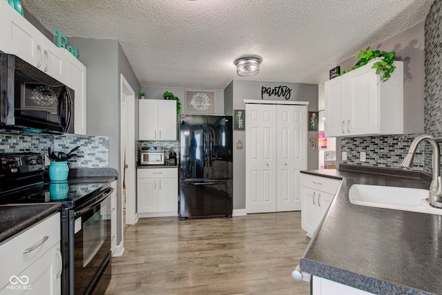 9593 W Constellation Dr, Pendleton, IN 46064 - kitchen with black appliances, dark countertops, light wood-style floors, and a textured ceiling