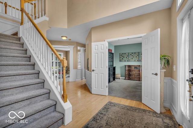 5865 Osage Dr, Carmel, IN 46033 - entryway featuring light wood-style flooring, decorative columns, stairs, and a wainscoted wall