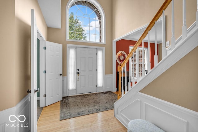 5865 Osage Dr, Carmel, IN 46033 - foyer entrance featuring wainscoting, stairs, a decorative wall, light wood finished floors, and a towering ceiling