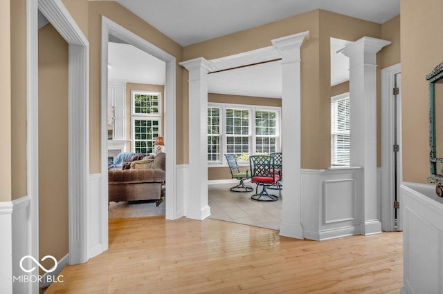 5865 Osage Dr, Carmel, IN 46033 - hall with decorative columns, a wainscoted wall, and light wood-style flooring