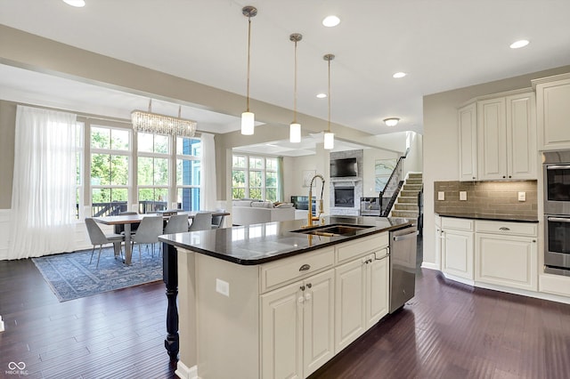 16711 Meadow Wood Dr, Noblesville, IN 46062 - kitchen featuring appliances with stainless steel finishes, dark countertops, dark wood finished floors, a glass covered fireplace, and backsplash