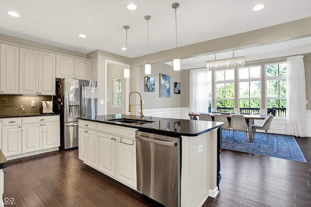 16711 Meadow Wood Dr, Noblesville, IN 46062 - kitchen with appliances with stainless steel finishes, dark countertops, plenty of natural light, wainscoting, and a kitchen island with sink