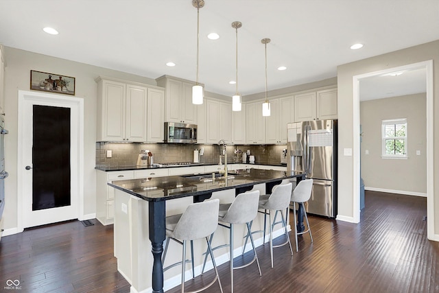 16711 Meadow Wood Dr, Noblesville, IN 46062 - kitchen with stainless steel appliances, dark countertops, tasteful backsplash, dark wood finished floors, and a kitchen breakfast bar