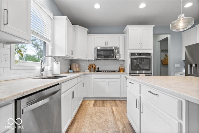 5542 Pennycress Dr, Noblesville, IN 46062 - kitchen featuring appliances with stainless steel finishes, light wood-style flooring, white cabinets, backsplash, and recessed lighting