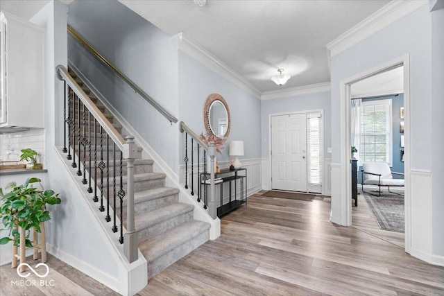 5542 Pennycress Dr, Noblesville, IN 46062 - entryway featuring stairway, light wood-style floors, ornamental molding, a textured ceiling, and wainscoting