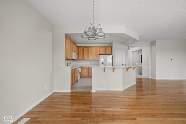 13019 Pinner Ave, Fishers, IN 46037 - kitchen featuring white appliances, light wood-type flooring, a chandelier, a kitchen bar, and light countertops