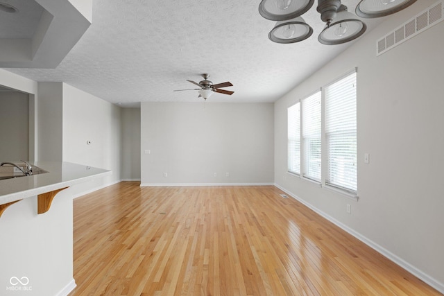 13019 Pinner Ave, Fishers, IN 46037 - unfurnished living room with a ceiling fan, light wood-style flooring, and a textured ceiling