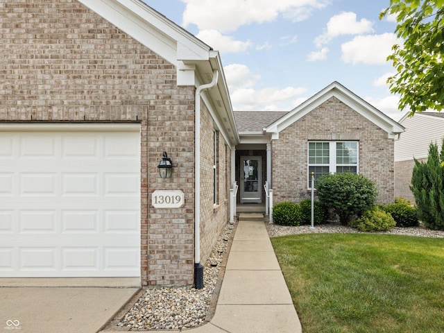 13019 Pinner Ave, Fishers, IN 46037 - view of exterior entry featuring brick siding, a yard, a garage, and concrete driveway