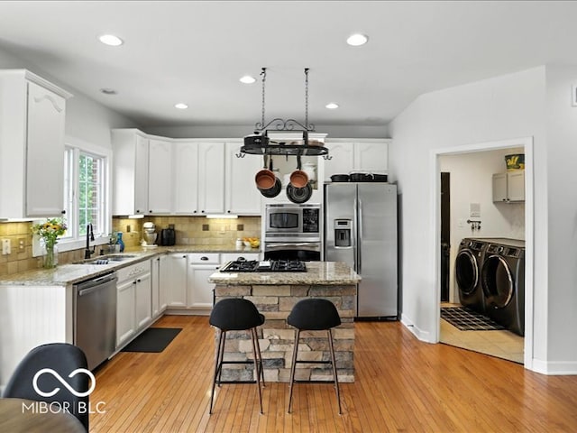 4233 Dartmoor Dr, Greenwood, IN 46143 - kitchen with appliances with stainless steel finishes, washing machine and dryer, light wood finished floors, backsplash, and recessed lighting