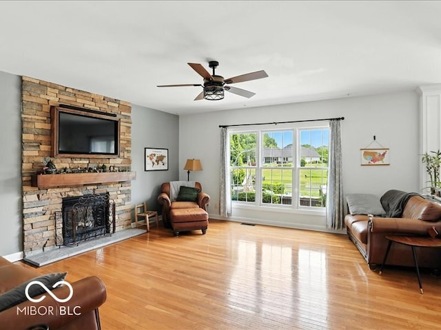 4233 Dartmoor Dr, Greenwood, IN 46143 - living area featuring light wood finished floors, a stone fireplace, and ceiling fan