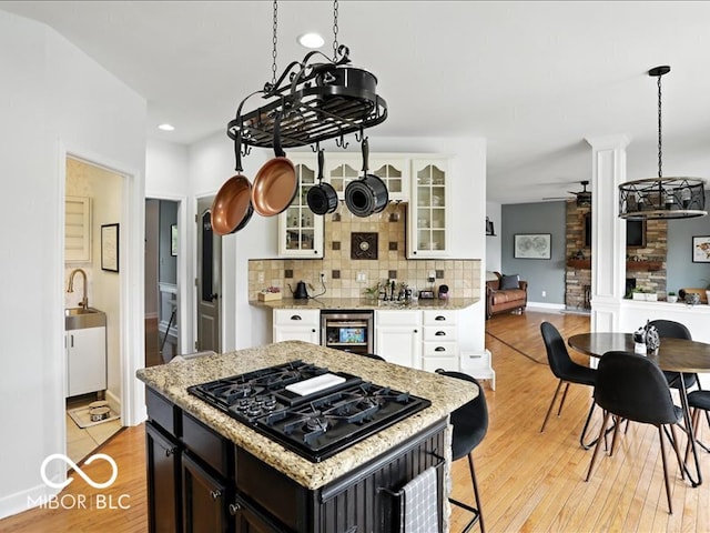 4233 Dartmoor Dr, Greenwood, IN 46143 - kitchen with black gas cooktop, wine cooler, light wood-style floors, glass insert cabinets, and backsplash
