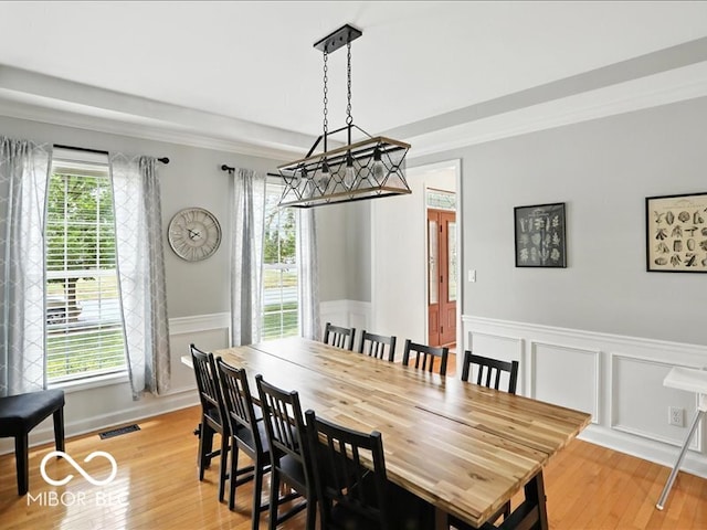 4233 Dartmoor Dr, Greenwood, IN 46143 - dining space featuring plenty of natural light, a wainscoted wall, light wood-style floors, crown molding, and a decorative wall