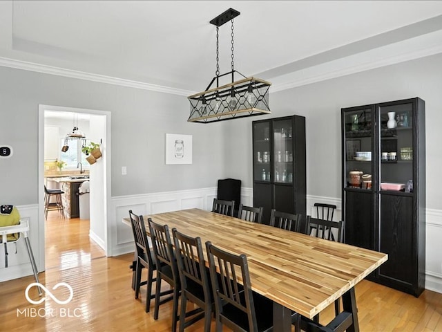 4233 Dartmoor Dr, Greenwood, IN 46143 - dining space featuring light wood-style floors, crown molding, a wainscoted wall, and a decorative wall