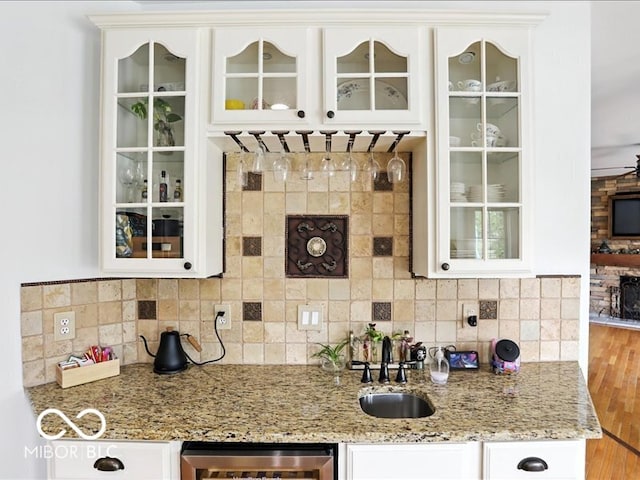 4233 Dartmoor Dr, Greenwood, IN 46143 - indoor wet bar featuring beverage cooler, decorative backsplash, wood finished floors, and a tile fireplace
