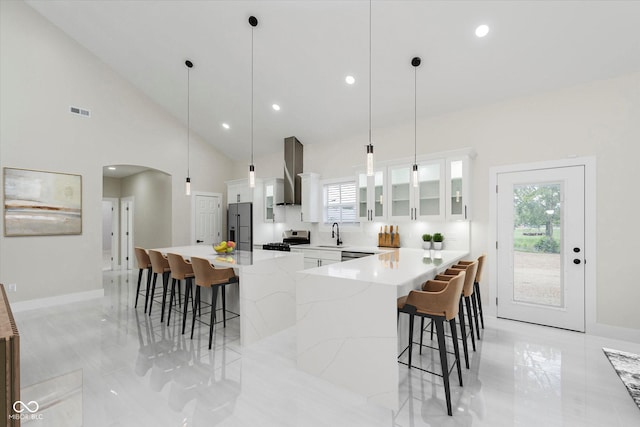 2125 N Pasadena St, Indianapolis, IN 46219 - kitchen with fridge with ice dispenser, stainless steel range oven, wall chimney exhaust hood, a kitchen breakfast bar, and arched walkways