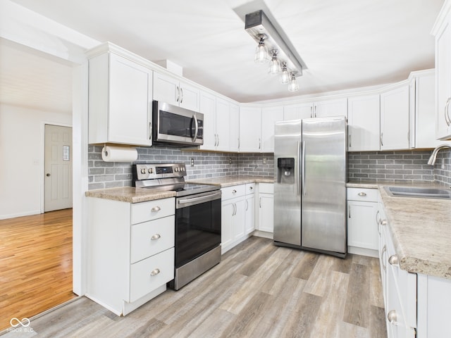 203 Plum St E, Frankton, IN 46044 - kitchen with appliances with stainless steel finishes, light countertops, light wood-style flooring, backsplash, and white cabinets