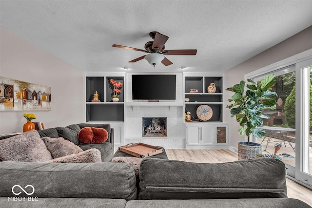 7502 Colony Cir, Indianapolis, IN 46260 - living room with wood finished floors, ceiling fan, a textured ceiling, and a brick fireplace