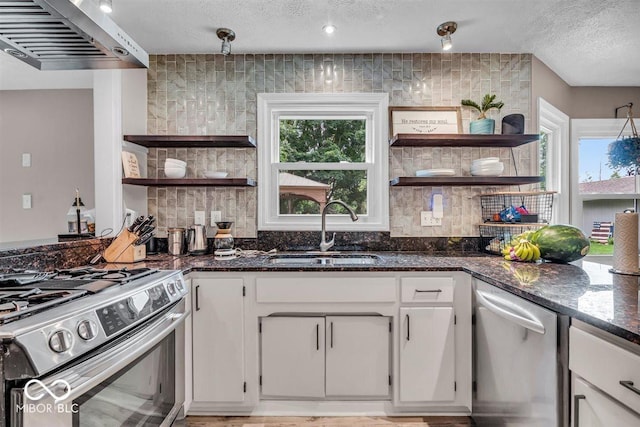 7502 Colony Cir, Indianapolis, IN 46260 - kitchen with open shelves, appliances with stainless steel finishes, exhaust hood, a textured ceiling, and dark stone countertops