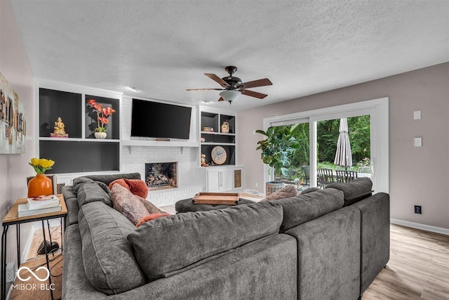 7502 Colony Cir, Indianapolis, IN 46260 - living area featuring light wood finished floors, a ceiling fan, a textured ceiling, and a fireplace