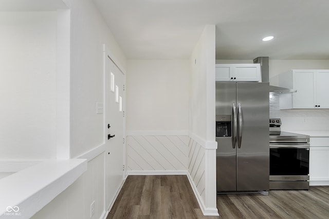 5134 Rinehart Ave, Indianapolis, IN 46241 - kitchen featuring appliances with stainless steel finishes, dark wood-style floors, wall chimney range hood, a wainscoted wall, and white cabinets