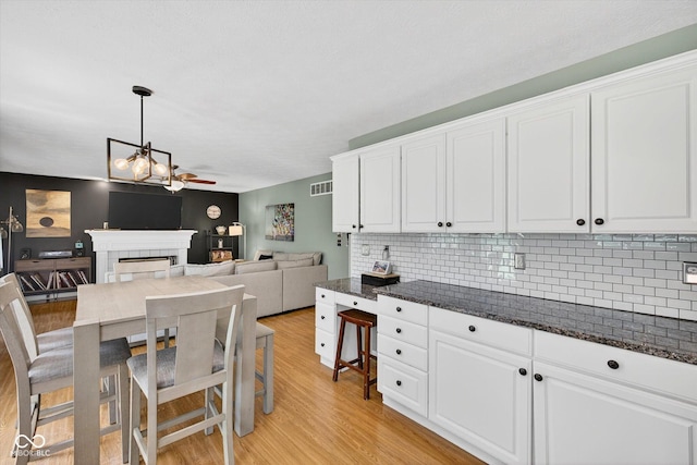 13470 Shakamac Dr, Carmel, IN 46032 - kitchen with a tile fireplace, light wood-style floors, and white cabinets