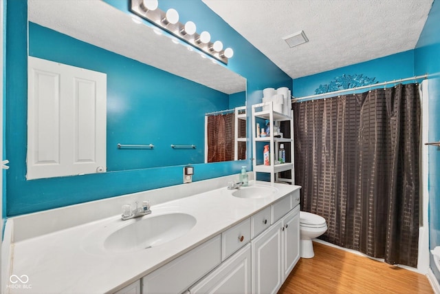 13470 Shakamac Dr, Carmel, IN 46032 - bathroom featuring double vanity, wood finished floors, and a textured ceiling