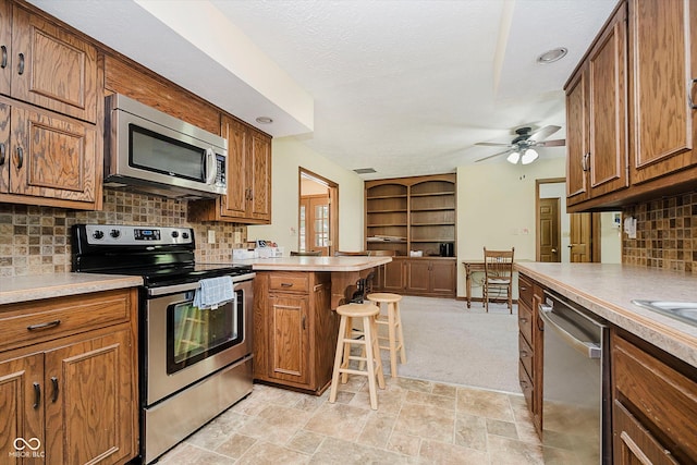 450 W 250 N, Lebanon, IN 46052 - kitchen featuring stainless steel appliances, a peninsula, brown cabinets, a ceiling fan, and a textured ceiling