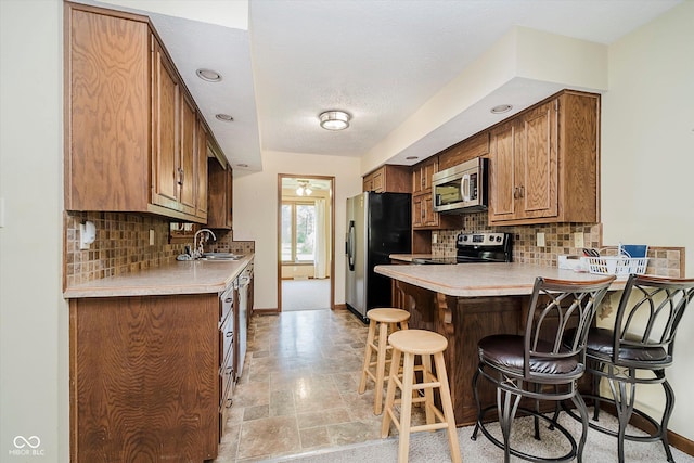 450 W 250 N, Lebanon, IN 46052 - kitchen featuring appliances with stainless steel finishes, a breakfast bar area, a peninsula, tasteful backsplash, and recessed lighting