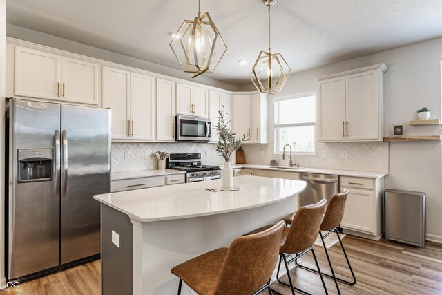 6902 Diamondleaf Way, Brownsburg, IN 46112 - kitchen featuring stainless steel appliances, light countertops, a kitchen island, light wood-type flooring, and hanging light fixtures