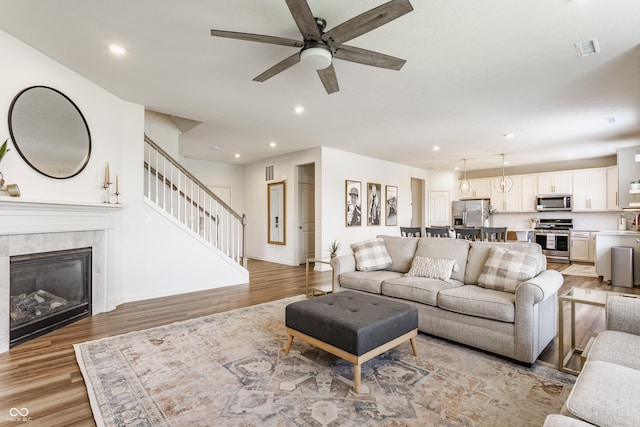 6902 Diamondleaf Way, Brownsburg, IN 46112 - living room with light wood-style flooring, a ceiling fan, stairway, a tiled fireplace, and recessed lighting