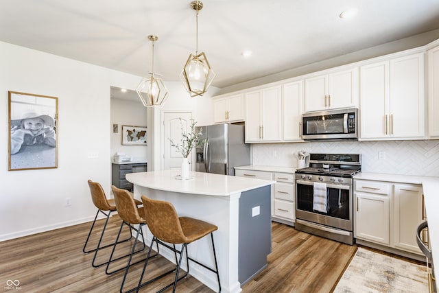 6902 Diamondleaf Way, Brownsburg, IN 46112 - kitchen featuring appliances with stainless steel finishes, a center island, a breakfast bar, tasteful backsplash, and wood finished floors