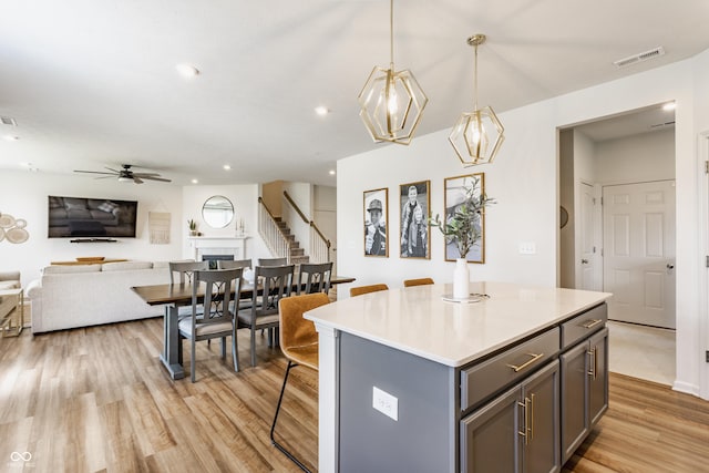 6902 Diamondleaf Way, Brownsburg, IN 46112 - kitchen with open floor plan, ceiling fan, gray cabinets, a center island, and light wood-style flooring