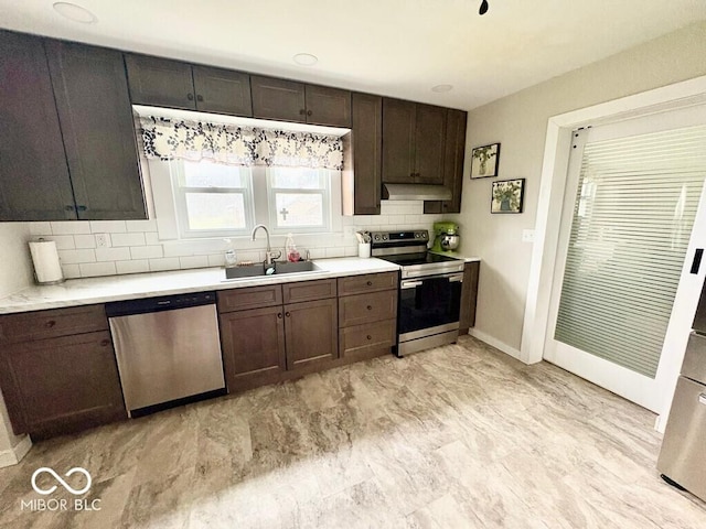 1076 N Old Highway 27, Winchester, IN 47394 - kitchen with appliances with stainless steel finishes, under cabinet range hood, tasteful backsplash, light countertops, and dark brown cabinets