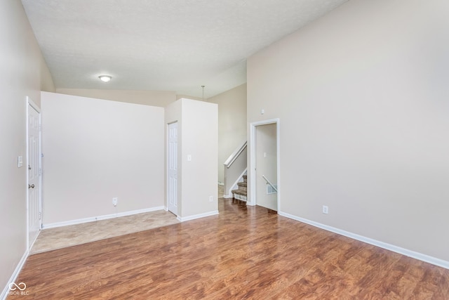 3515 Bearwood Ct, Indianapolis, IN 46235 - empty room with wood finished floors, stairway, and vaulted ceiling