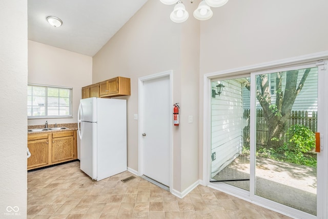 3515 Bearwood Ct, Indianapolis, IN 46235 - kitchen with freestanding refrigerator, high vaulted ceiling, a chandelier, light countertops, and brown cabinets